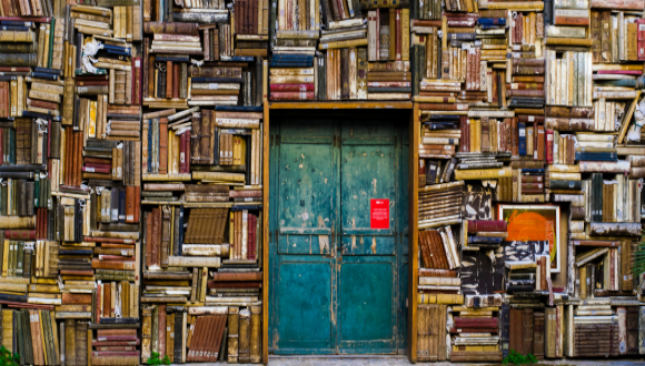 Blue wooden door in the wall painted as piles of books